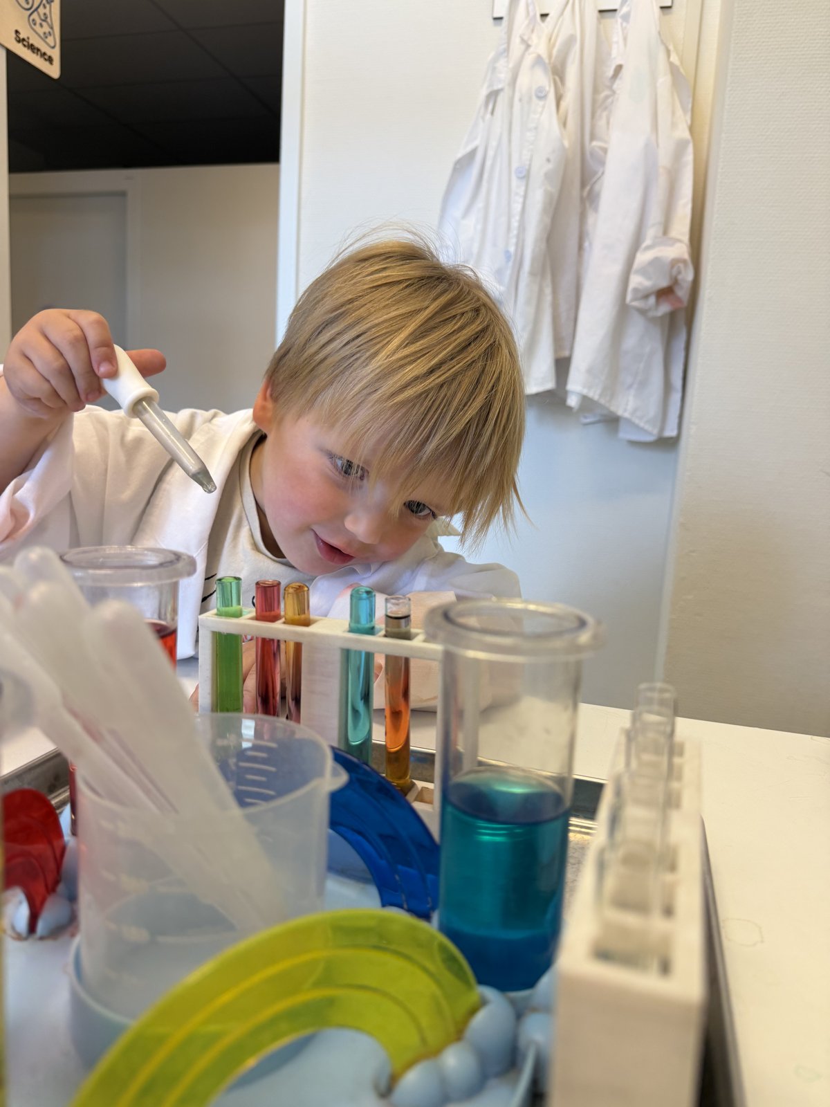 Kleuter experimenteert met een pipet en gekleurd water bij vulvormen