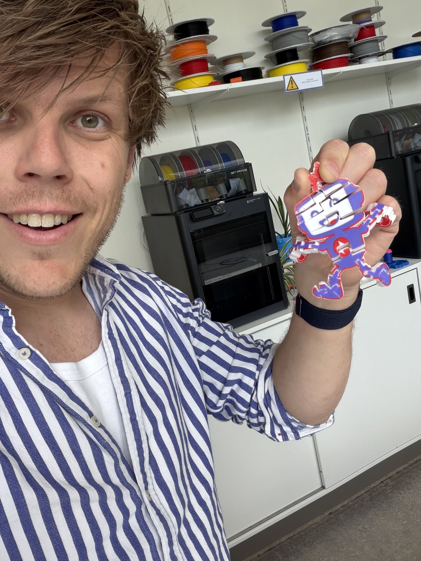 Meester Sander met een 3D-geprinte robot bij de 3D-printer